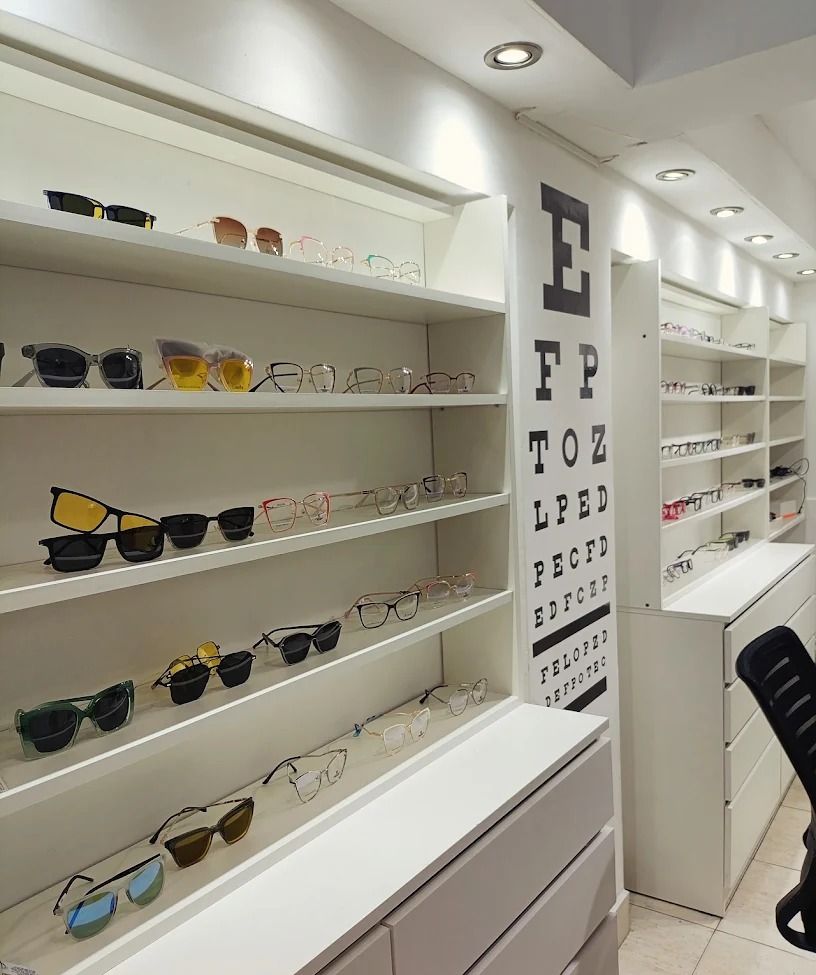 Interior de Óptica Lux: estanterías blancas con armazones y lentes de sol en exhibición